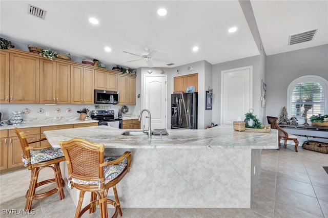 kitchen with ceiling fan, light tile patterned floors, sink, an island with sink, and stainless steel appliances