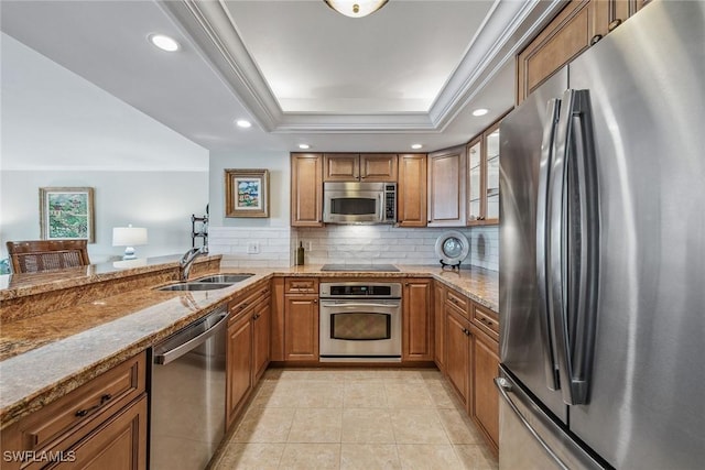 kitchen featuring sink, appliances with stainless steel finishes, backsplash, light stone counters, and a raised ceiling