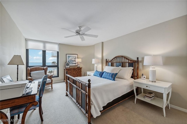 carpeted bedroom featuring a water view and ceiling fan