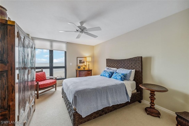 bedroom featuring light colored carpet, ceiling fan, and a water view