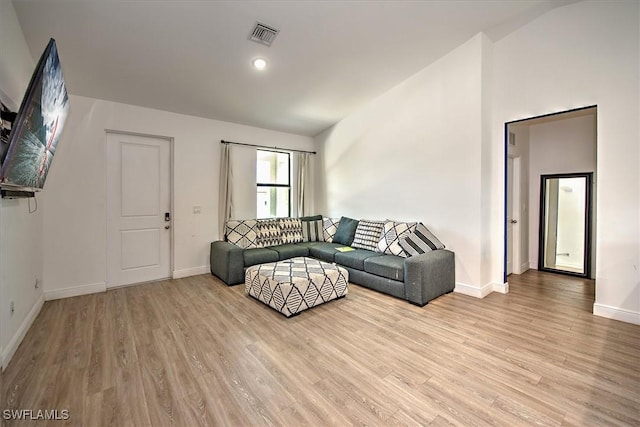 living room with light hardwood / wood-style flooring and vaulted ceiling