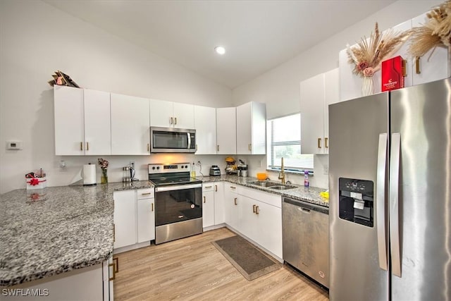 kitchen featuring appliances with stainless steel finishes, sink, white cabinets, dark stone countertops, and light hardwood / wood-style floors