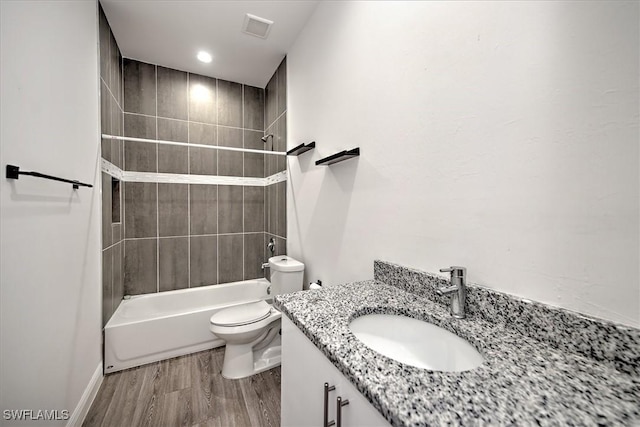 full bathroom featuring wood-type flooring, toilet, tiled shower / bath, and vanity