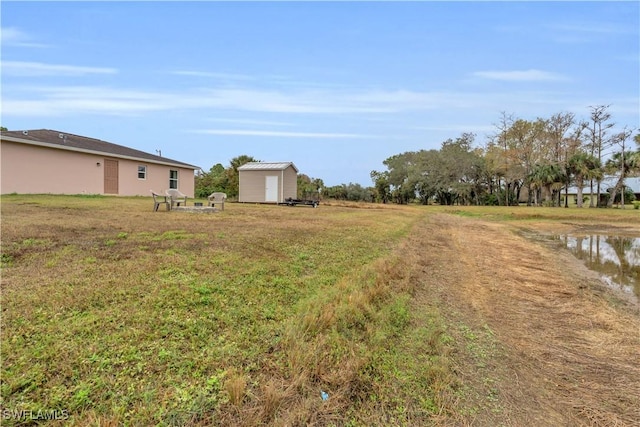 view of yard featuring a water view and a shed