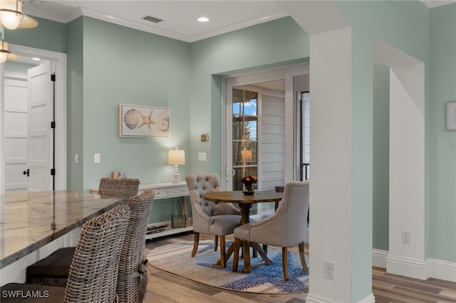 dining space featuring ornamental molding and light hardwood / wood-style flooring