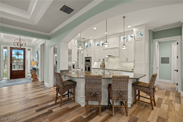 kitchen featuring stone countertops, light hardwood / wood-style floors, hanging light fixtures, and white cabinets