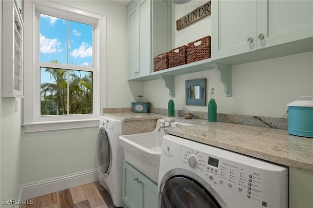 clothes washing area featuring cabinets, washer and dryer, and light wood-type flooring