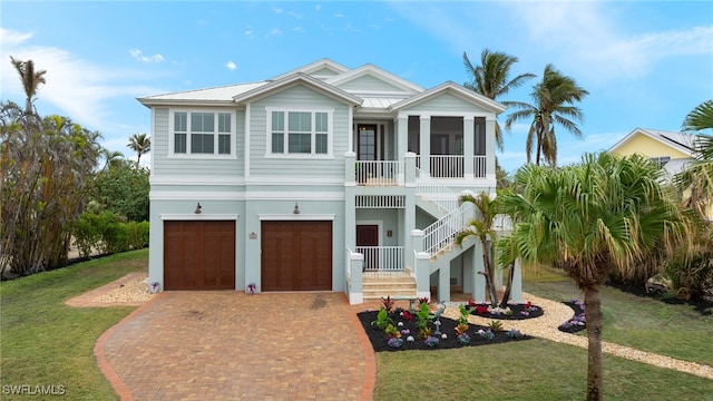 coastal inspired home with a garage, a sunroom, and a front lawn