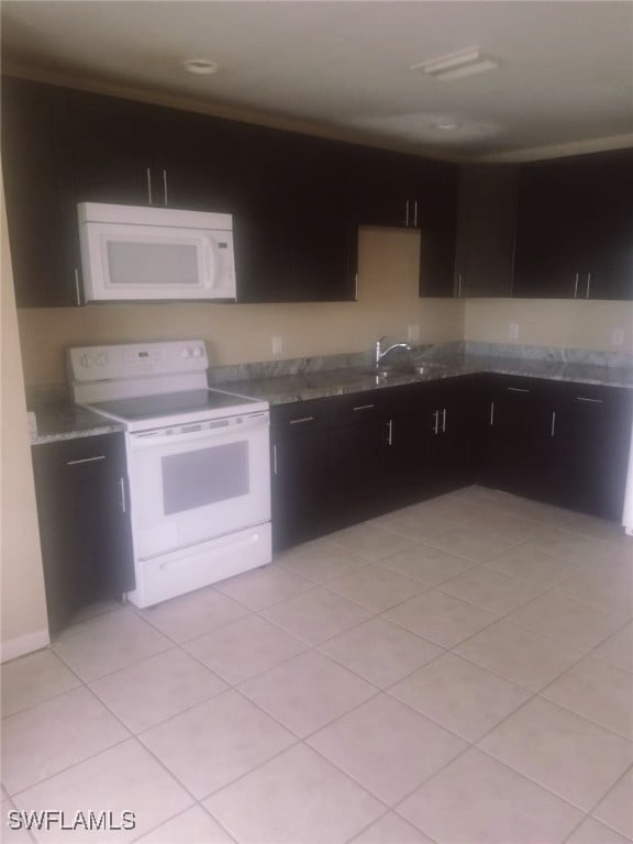 kitchen featuring dark brown cabinetry, white appliances, and light tile patterned flooring