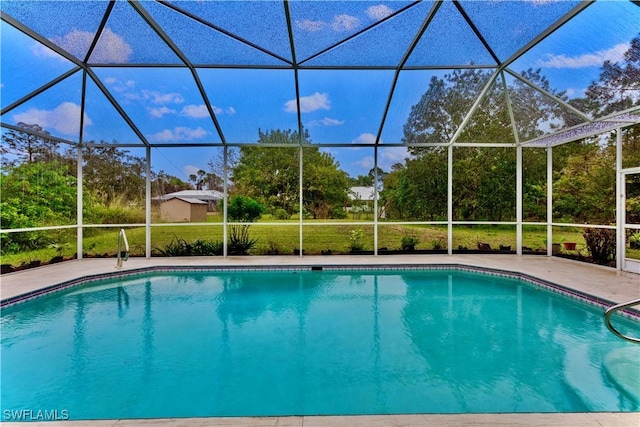 view of swimming pool featuring a lanai and a lawn