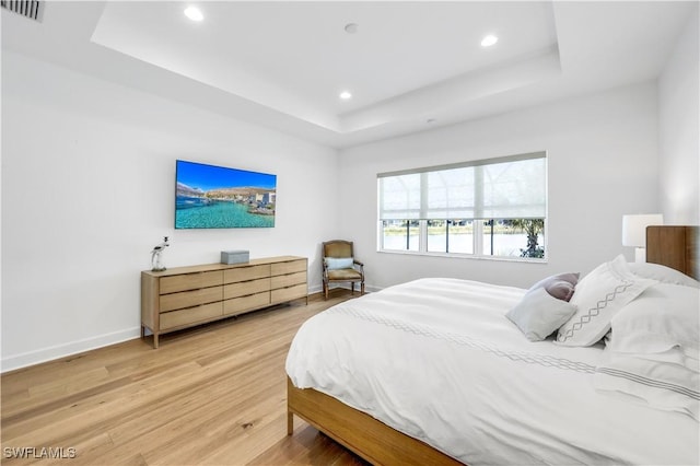 bedroom with a raised ceiling and hardwood / wood-style floors