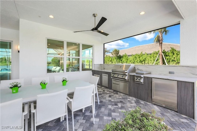 view of patio featuring an outdoor kitchen, area for grilling, ceiling fan, and a wet bar