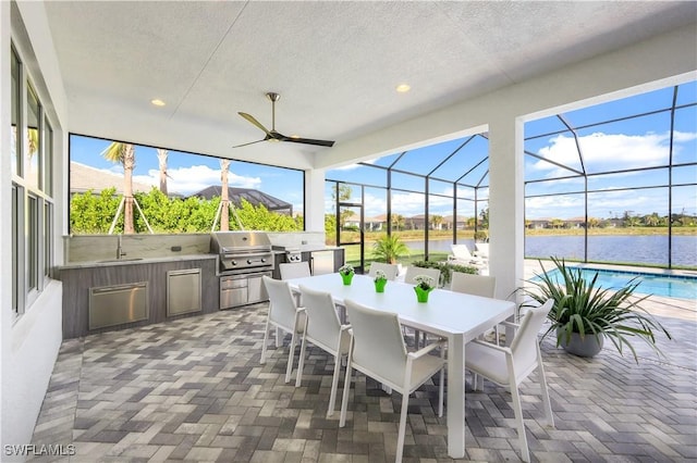 sunroom with sink, ceiling fan, and a water view