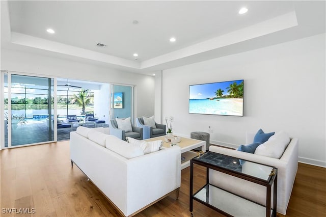 living room with hardwood / wood-style floors and a raised ceiling