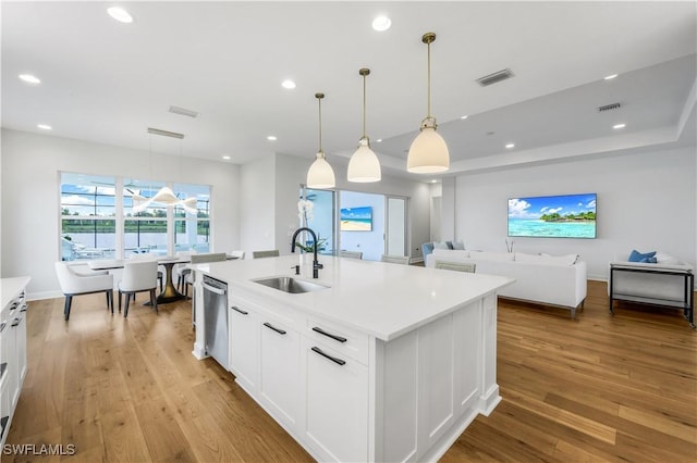 kitchen featuring sink, hanging light fixtures, an island with sink, white cabinets, and stainless steel dishwasher