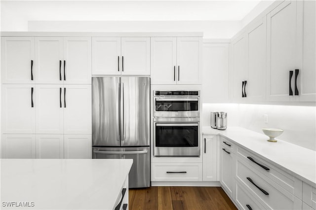 kitchen with dark wood-type flooring, appliances with stainless steel finishes, and white cabinets