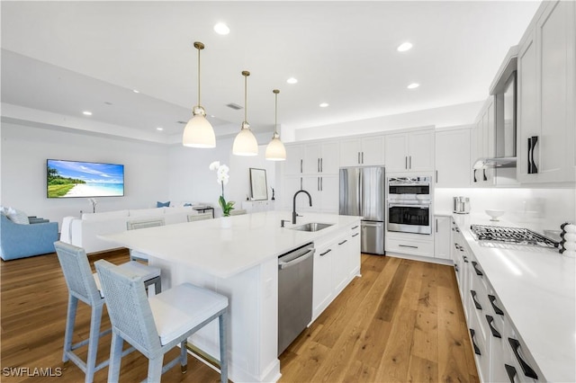 kitchen featuring an island with sink, appliances with stainless steel finishes, sink, and white cabinets