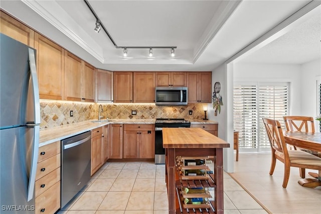 kitchen with wood counters, sink, backsplash, light tile patterned floors, and stainless steel appliances