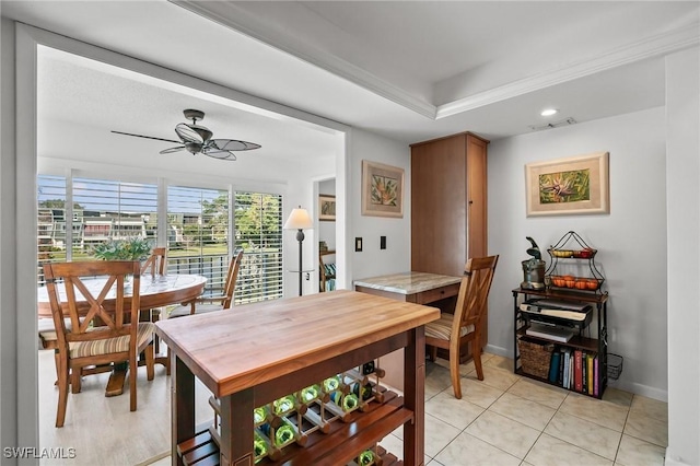 dining space with ceiling fan, a raised ceiling, and light tile patterned floors