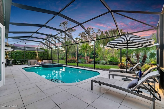 pool at dusk featuring an in ground hot tub, a patio, and glass enclosure