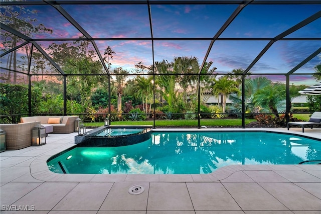 pool at dusk with an in ground hot tub, outdoor lounge area, glass enclosure, and a patio area