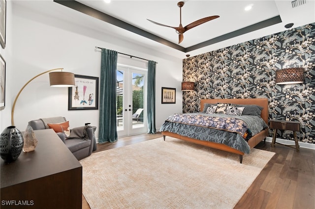 bedroom featuring access to outside, ceiling fan, a raised ceiling, dark wood-type flooring, and french doors