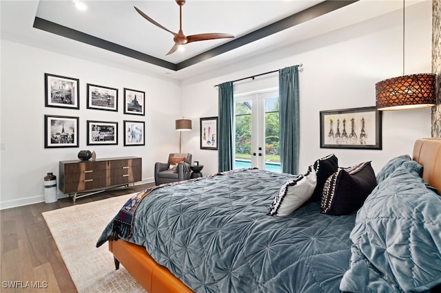 bedroom with french doors, dark wood-type flooring, access to outside, a raised ceiling, and ceiling fan