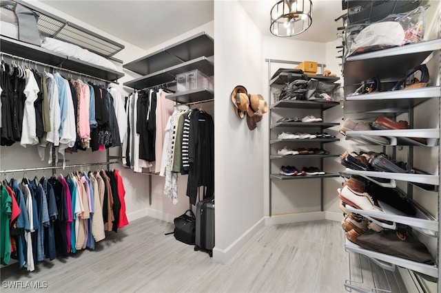 walk in closet featuring light hardwood / wood-style floors and a notable chandelier