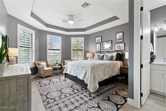 bedroom featuring ceiling fan, a raised ceiling, and light hardwood / wood-style flooring