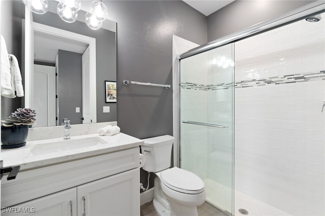 bathroom with a shower with door, vanity, and toilet