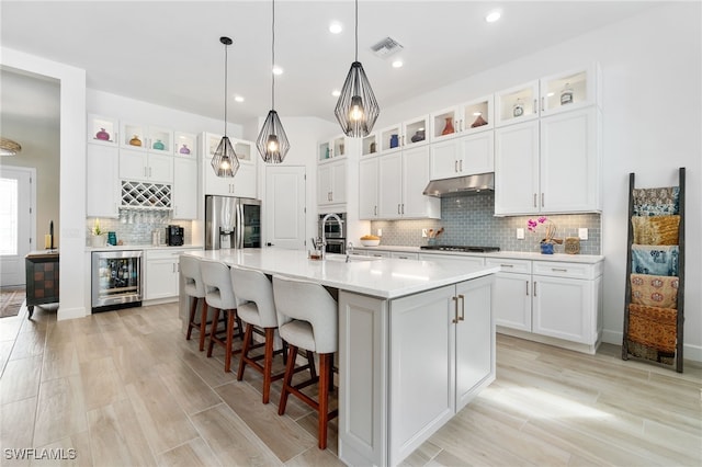 kitchen with a kitchen island with sink, beverage cooler, white cabinets, and stainless steel refrigerator with ice dispenser