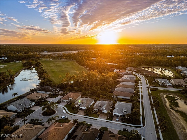 aerial view at dusk featuring a water view