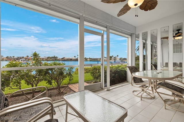 sunroom featuring plenty of natural light, ceiling fan, and a water view