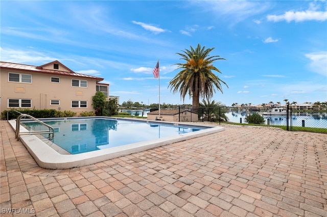 view of swimming pool featuring a water view and a patio area