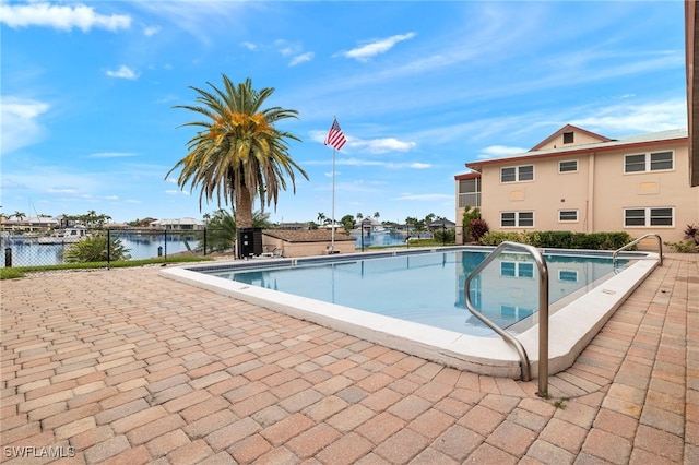 view of swimming pool featuring a water view and a patio area