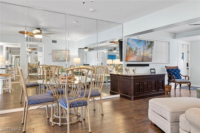 dining area featuring ceiling fan, dark wood-type flooring, and a textured ceiling