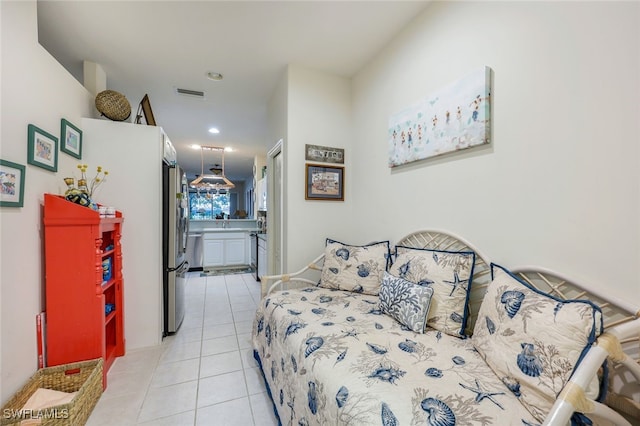 bedroom featuring light tile patterned flooring, ensuite bath, and stainless steel refrigerator