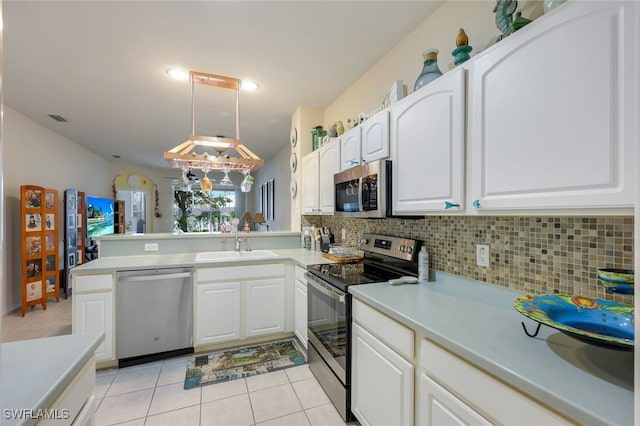 kitchen featuring decorative light fixtures, white cabinets, appliances with stainless steel finishes, and kitchen peninsula