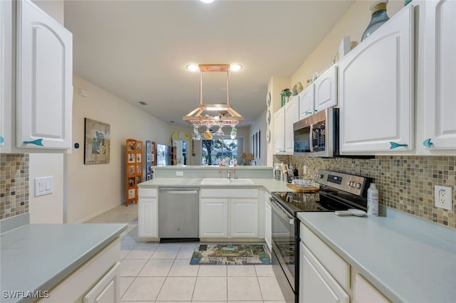 kitchen with decorative backsplash, hanging light fixtures, white cabinets, and stainless steel appliances