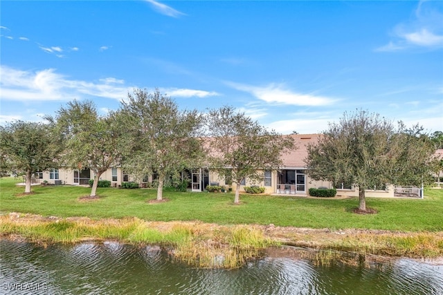 rear view of house with a water view and a lawn