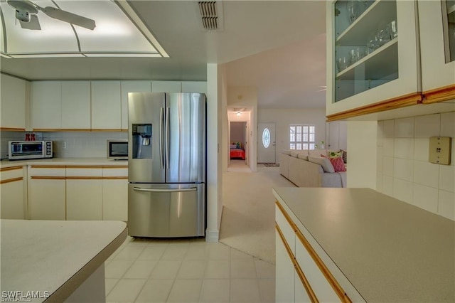 kitchen featuring white cabinetry, backsplash, ceiling fan, and stainless steel refrigerator with ice dispenser