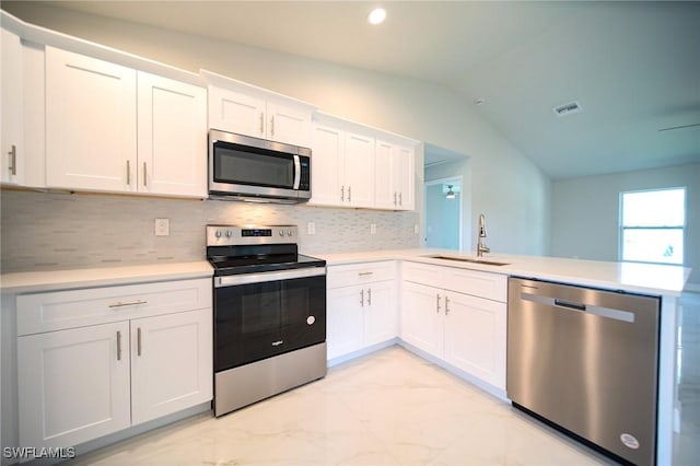 kitchen with kitchen peninsula, sink, white cabinets, lofted ceiling, and stainless steel appliances