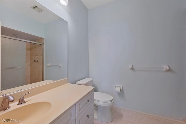 bathroom with tile patterned flooring, vanity, a shower with shower door, and toilet