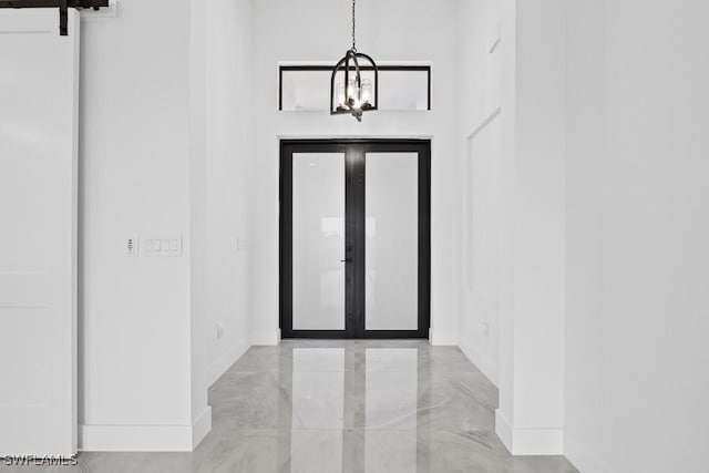 entryway featuring french doors, a barn door, and a notable chandelier