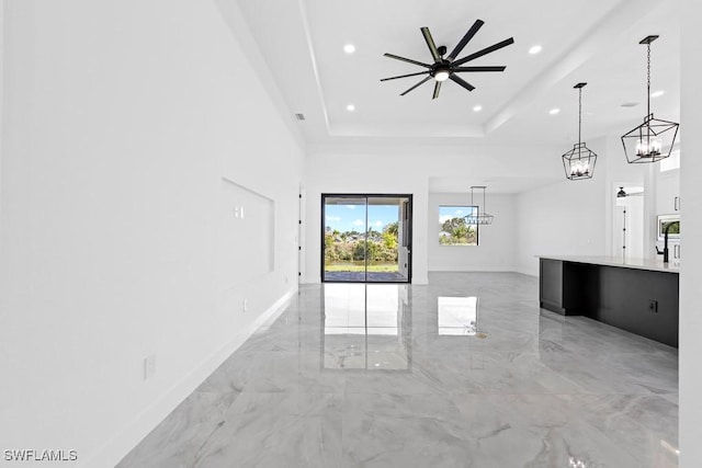 unfurnished living room with a tray ceiling and ceiling fan