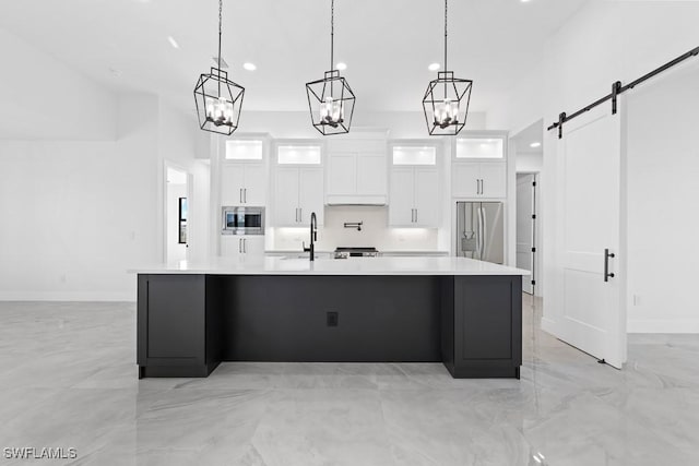 kitchen with white cabinetry, a large island, stainless steel appliances, and a barn door