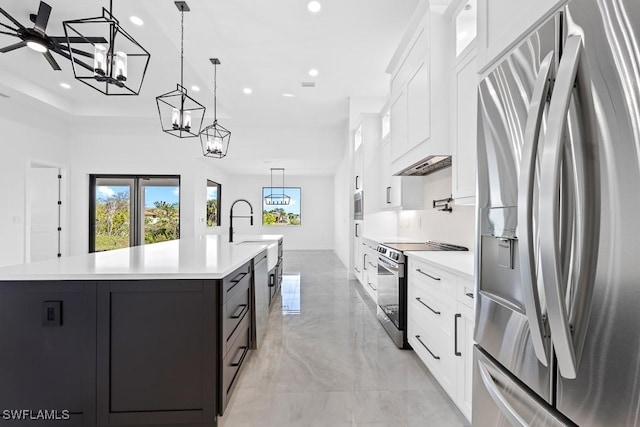 kitchen with appliances with stainless steel finishes, pendant lighting, white cabinetry, an island with sink, and sink