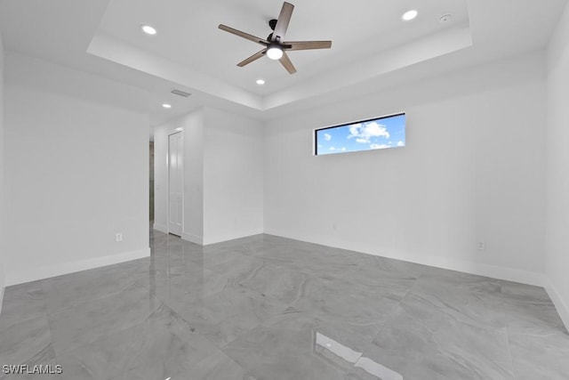 spare room featuring ceiling fan and a raised ceiling