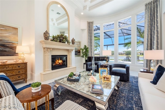 living room featuring a towering ceiling, ornamental molding, and a high end fireplace