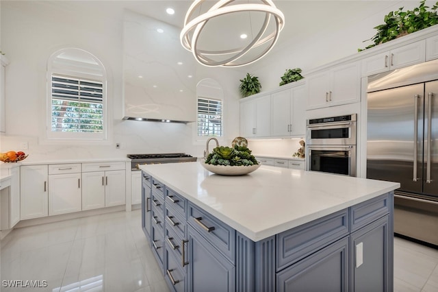 kitchen with a kitchen island, white cabinetry, appliances with stainless steel finishes, and pendant lighting